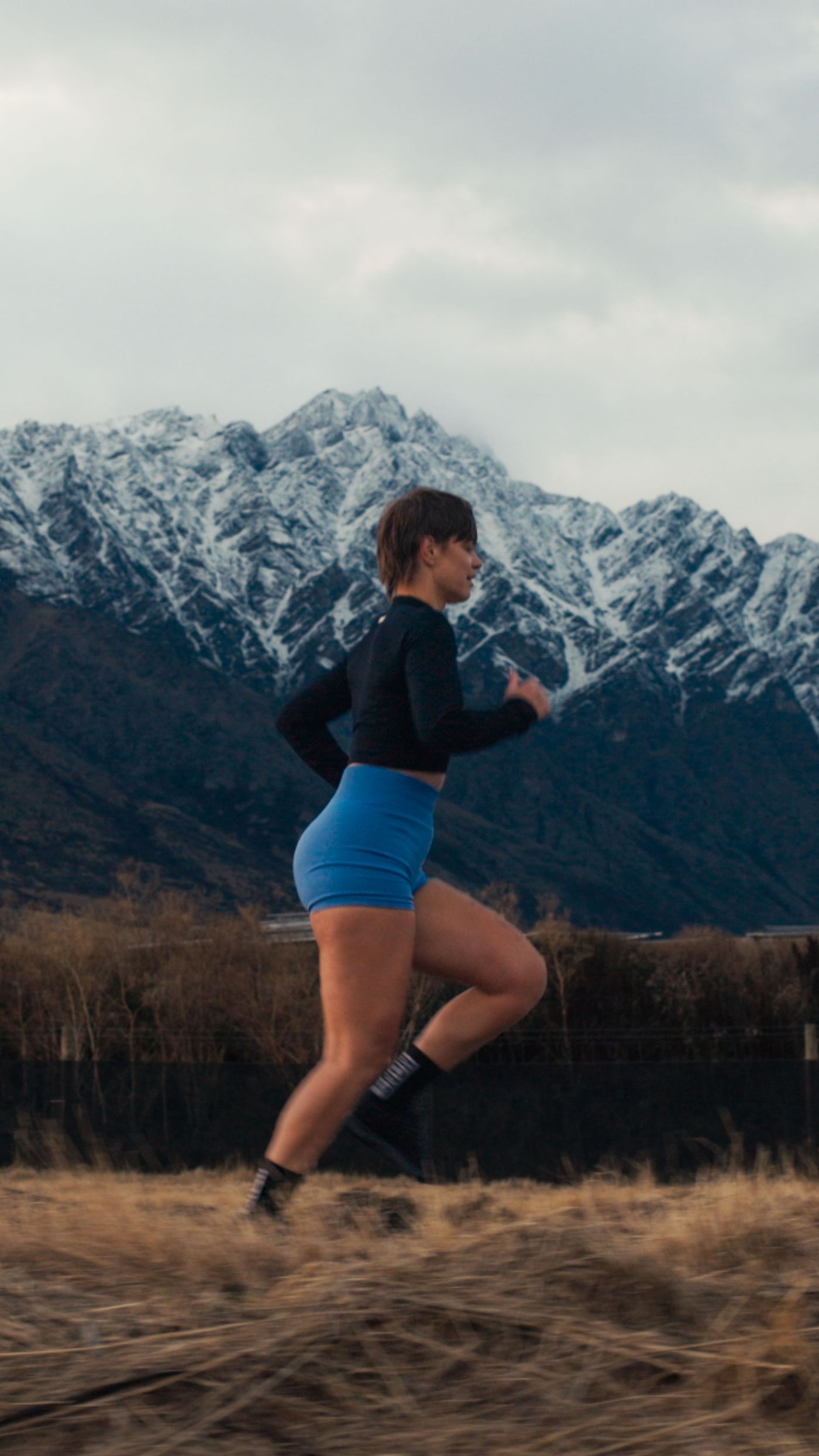 A runner stretching with the mountains behind